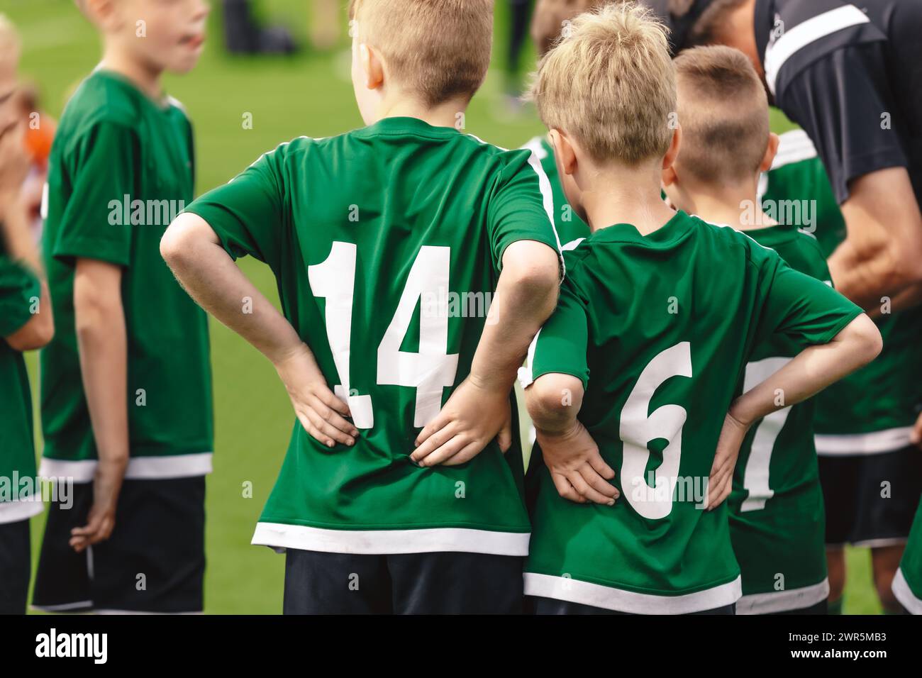 Children in sports team coached by young coach. a Soccer competition game for school kids. Kids listen to the coach's advice during the half-time brea Stock Photo