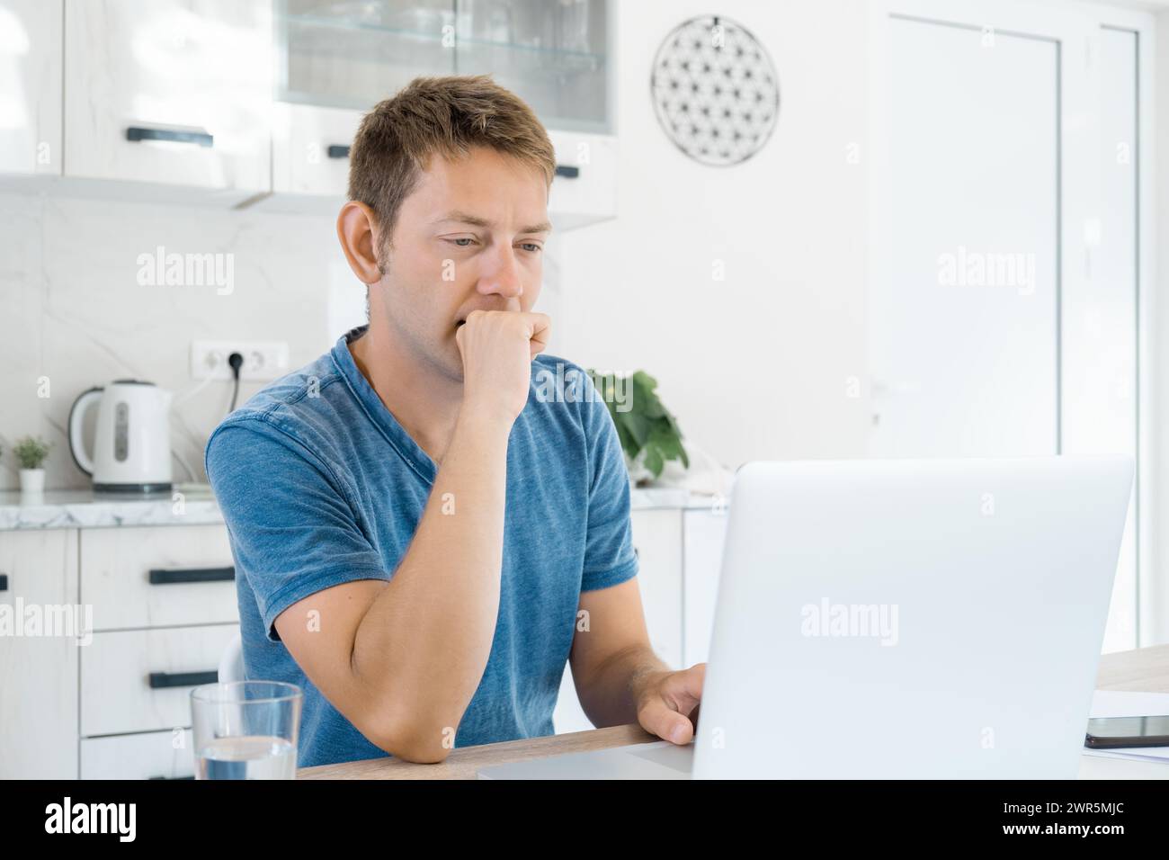 Thoughtfull attractive man working on laptop online at home, using internet. Concentrated male freelancer using computer for distance work. Remote job Stock Photo