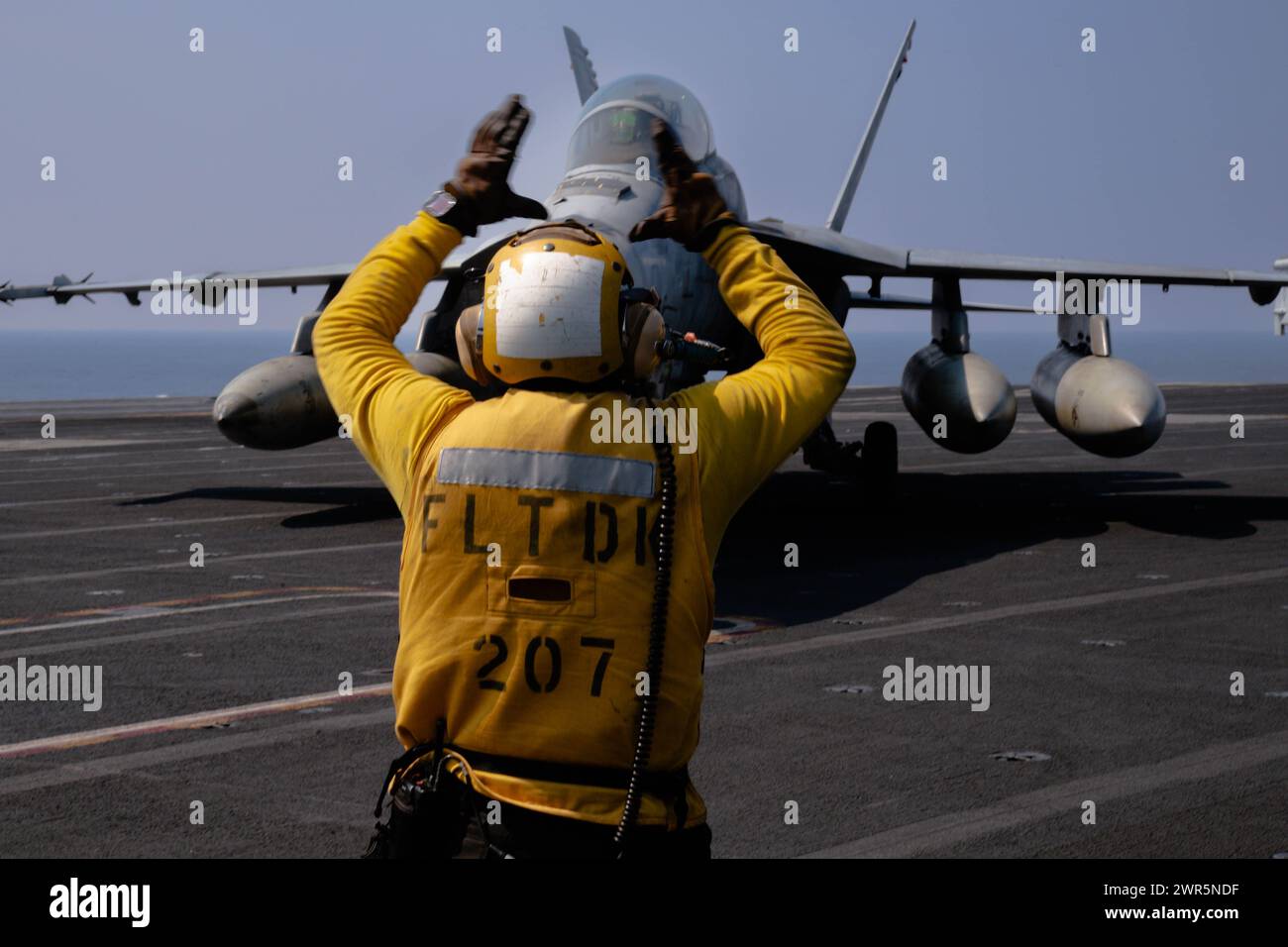 SOUTH CHINA SEA (March 8, 2024) U.S. Navy Aviation Boatswain’s Mate (Handling) 2nd Class Steven Ramirez, from Texas, directs an F/A-18F Super Hornet Stock Photo