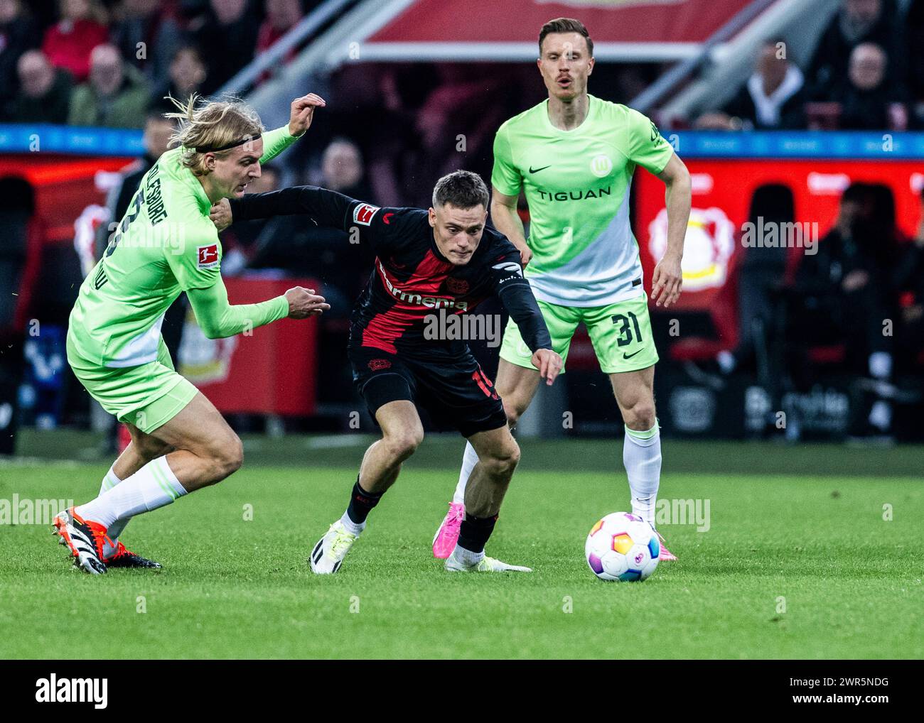 Leverkusen, Bayarena, 10.03.2024: Florian Wirtz (Leverkusen) (M) gegen Sebastiaan Bornauw (L) und Yannick Gerhardt (beide Wolfsburg) am Ball beim Spie Stock Photo