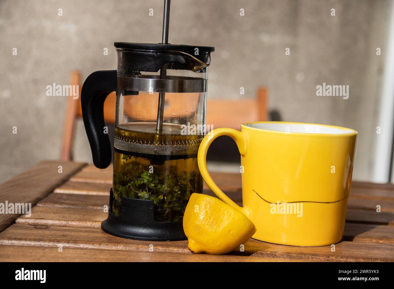 Teapot (French press) with half lemon and teapot at wooden table on the balcony, morning tea time, aromatic aromatherapy fresh and herbal, organic tea Stock Photo