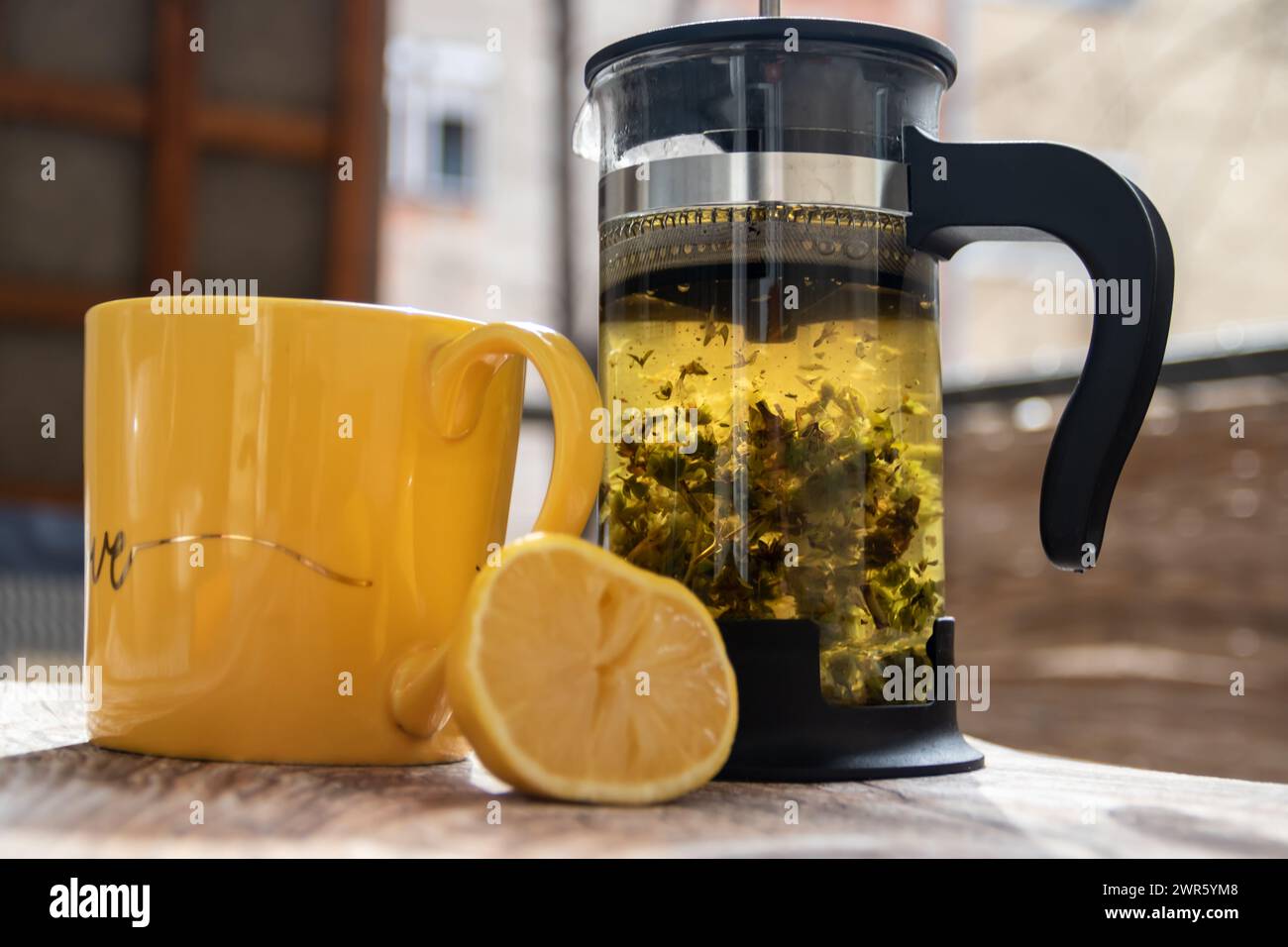 Teapot (French press) with half lemon and teapot at wooden table on the balcony, morning tea time, aromatic aromatherapy fresh and herbal, organic tea Stock Photo