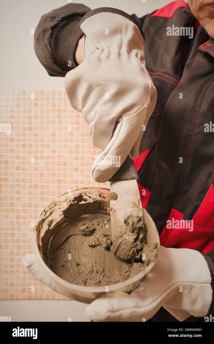 Older man working in empty apartment repairing holes in walls Stock