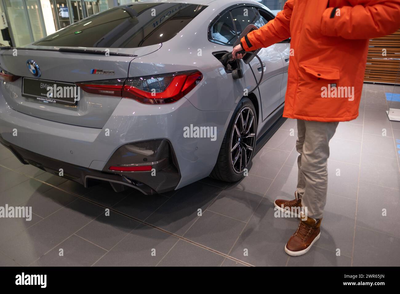 man choosing grey electric BMW i4 five-door electric liftback class D in showroom, Exterieur vehicle in studio, driving safety, technology automotive Stock Photo