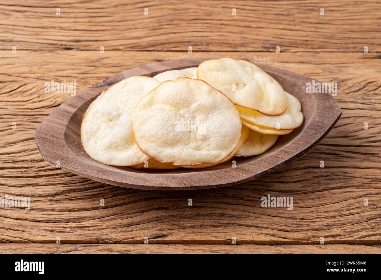 Smoked provolone cheese chips in a bowl over wooden table. Stock Photo