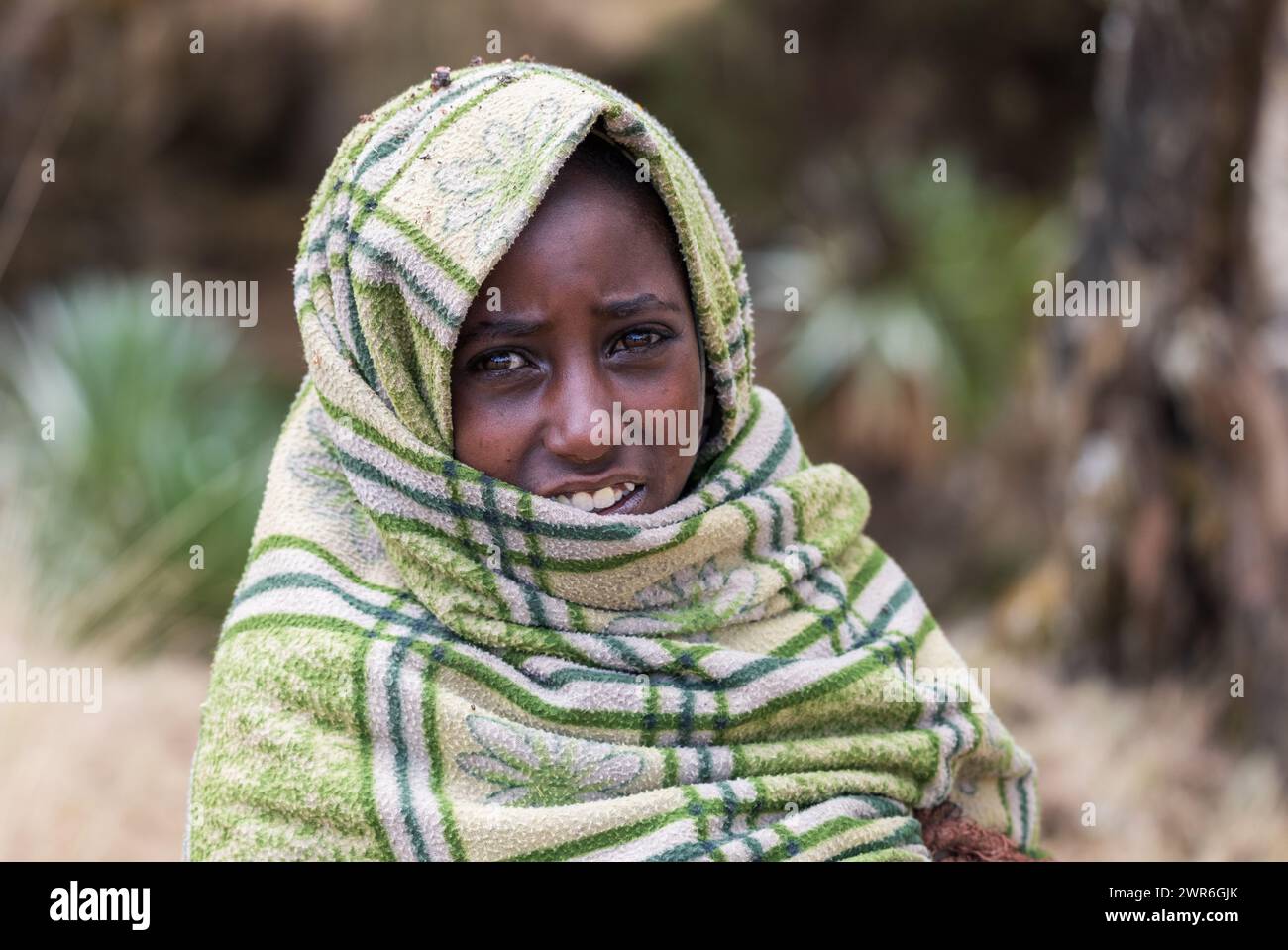SIMIEN MOUNTAIN, ETHIOPIA, APRIL 25.2019, Little Ethiopian shepherdess girl veiled in a blanket in cold morning. Simien Mountains, Ethiopia, April 25. Stock Photo