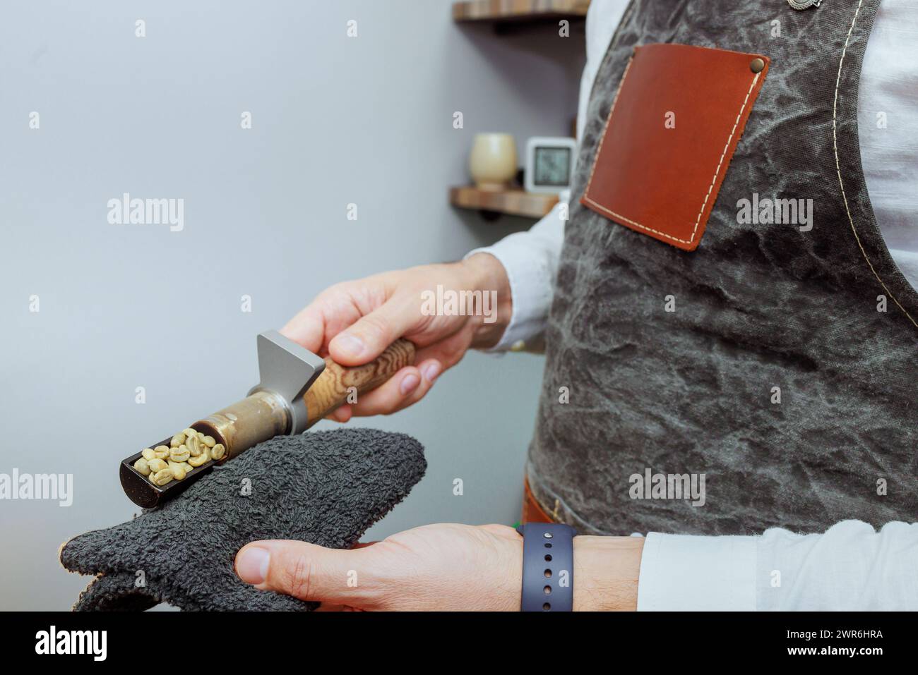 Operator of natural coffee roasting oven checks roast of variety coffee