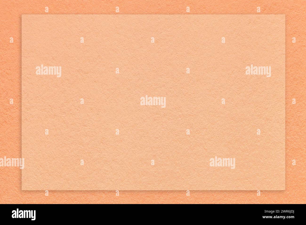 Color of year 2024. Texture of craft peach fuzz color paper background with coral border, macro. Structure of vintage kraft cardboard with empty frame Stock Photo