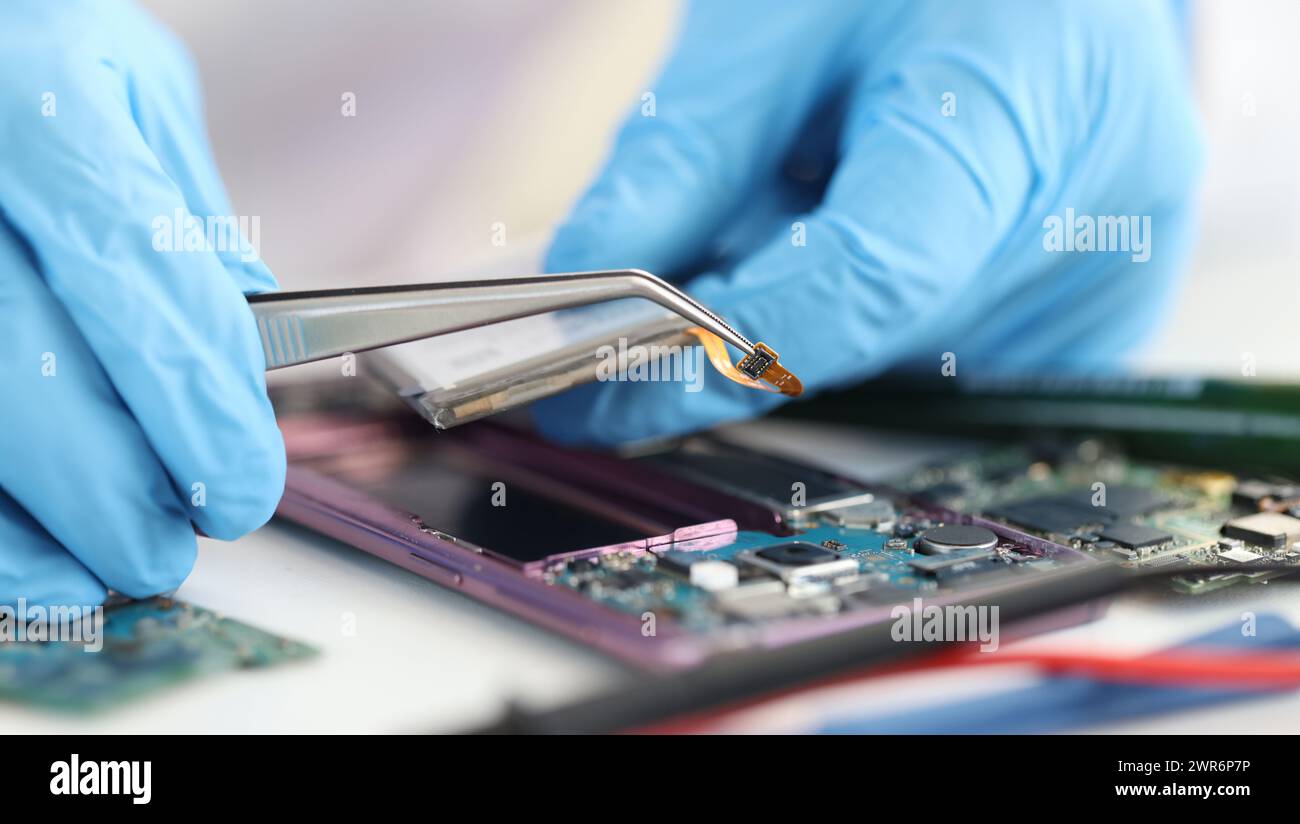 Master repairman inserting microchip into mobile phones closeup Stock Photo