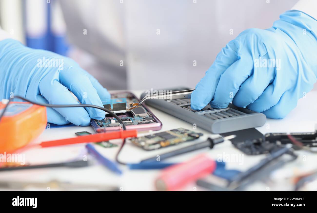 Master repairman inserting microchip into mobile phone closeup Stock Photo