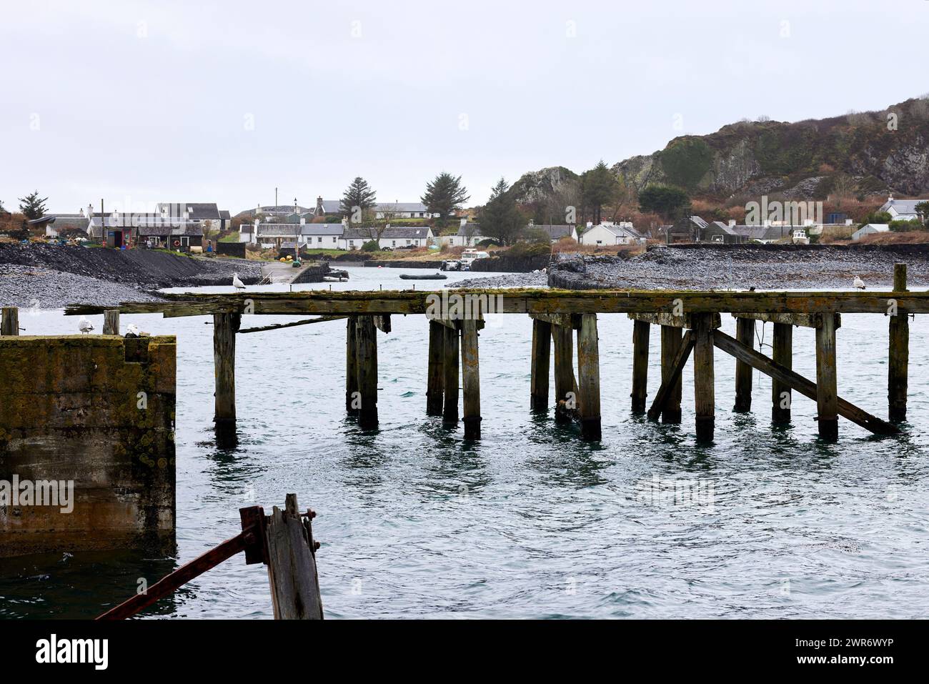 Across the Sound of Easdale, the derelict pier stands as testament to the past slate industry Stock Photo