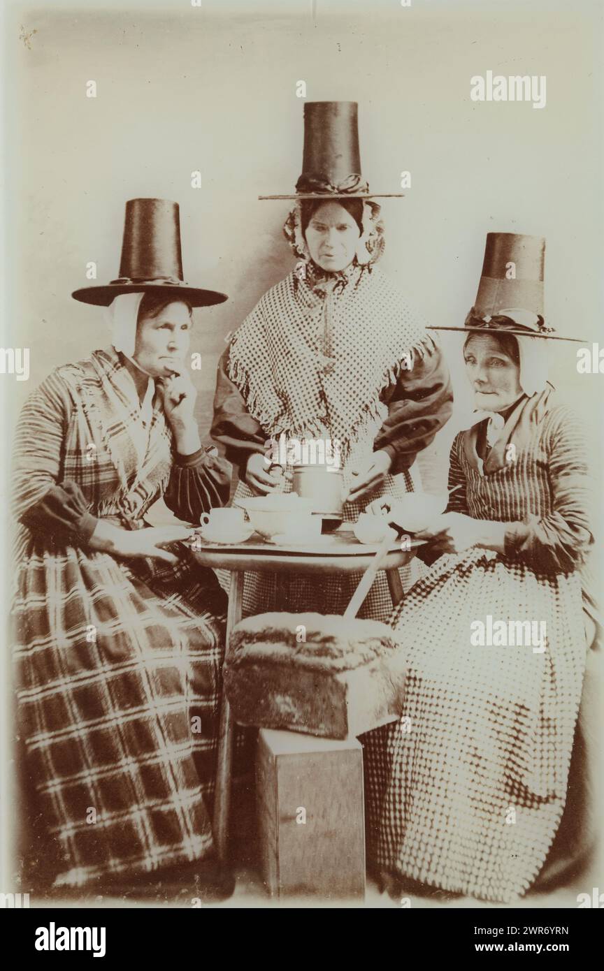 Group portrait of three unknown women at a tea table in Hindelooper costume, anonymous, 1890 - 1920, glass, height 207 mm × width 134 mm × thickness 5 mm, photograph Stock Photo