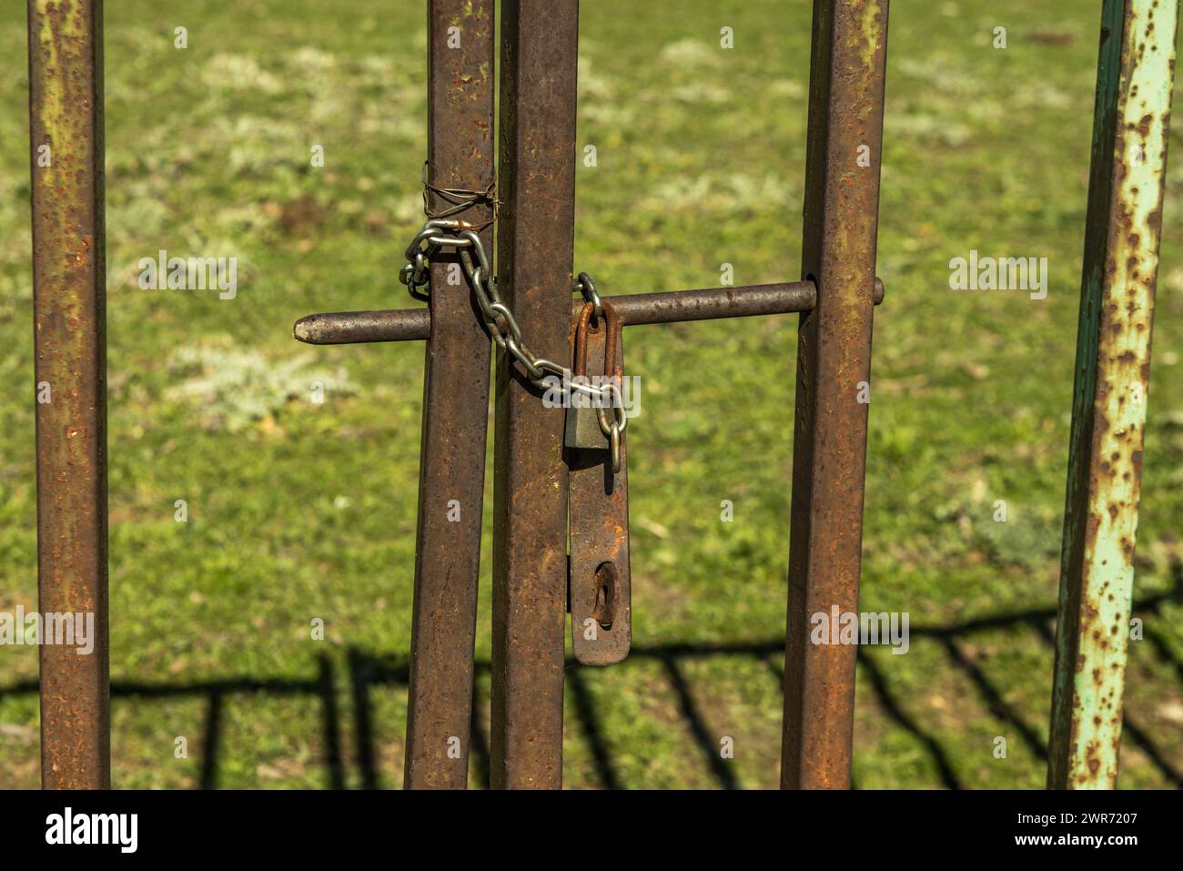 Rusty metal fence of a plot with a chain and a padlock Stock Photo