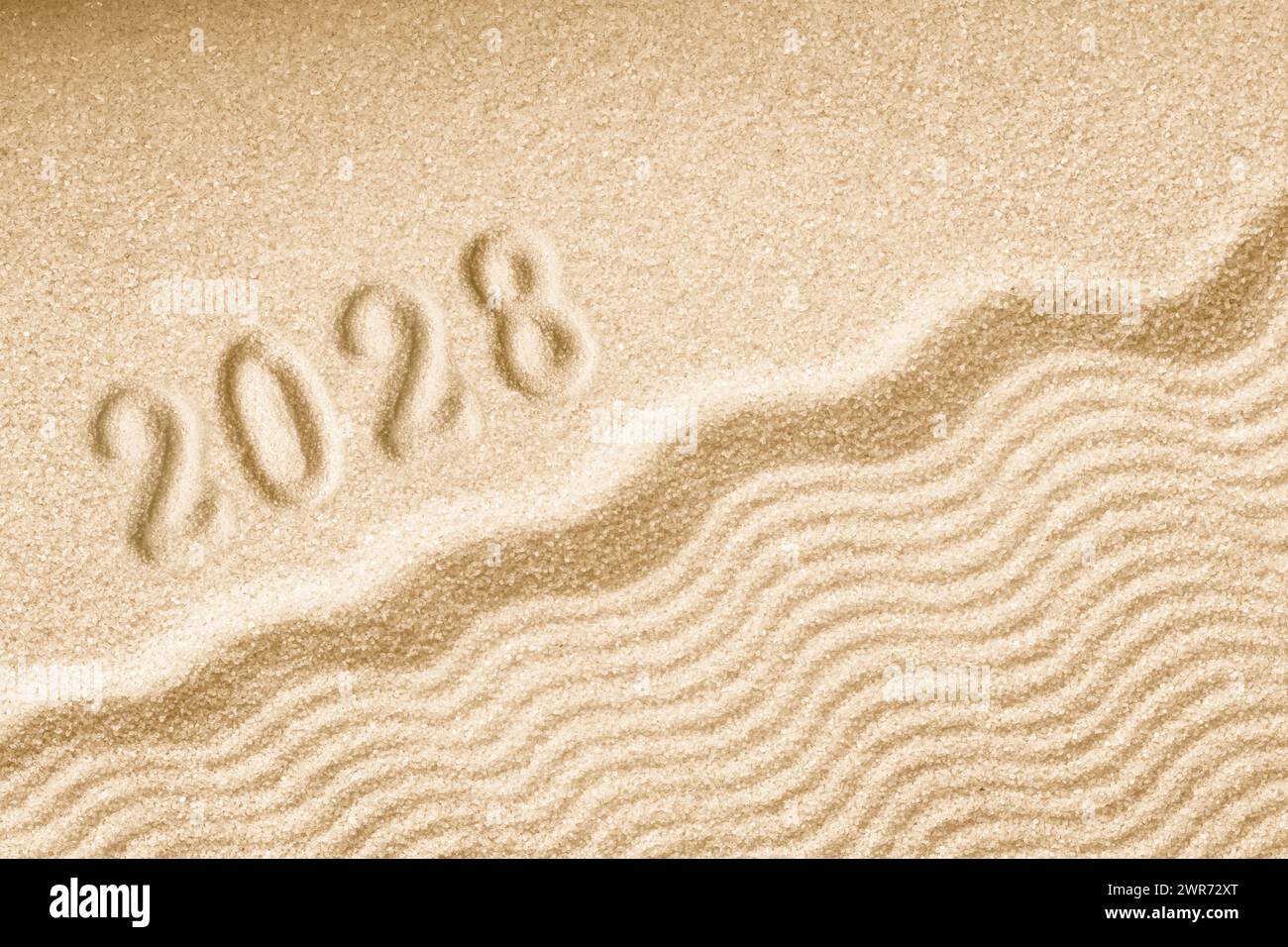 Imprints of numbers 2028 happy new year on a golden sand waves background Stock Photo