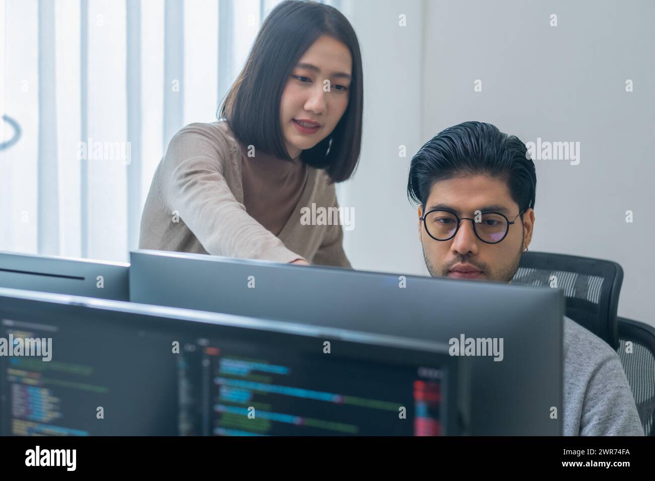 asian and Indian Developer team discussion feedback analysis coding data with software computer at office Stock Photo