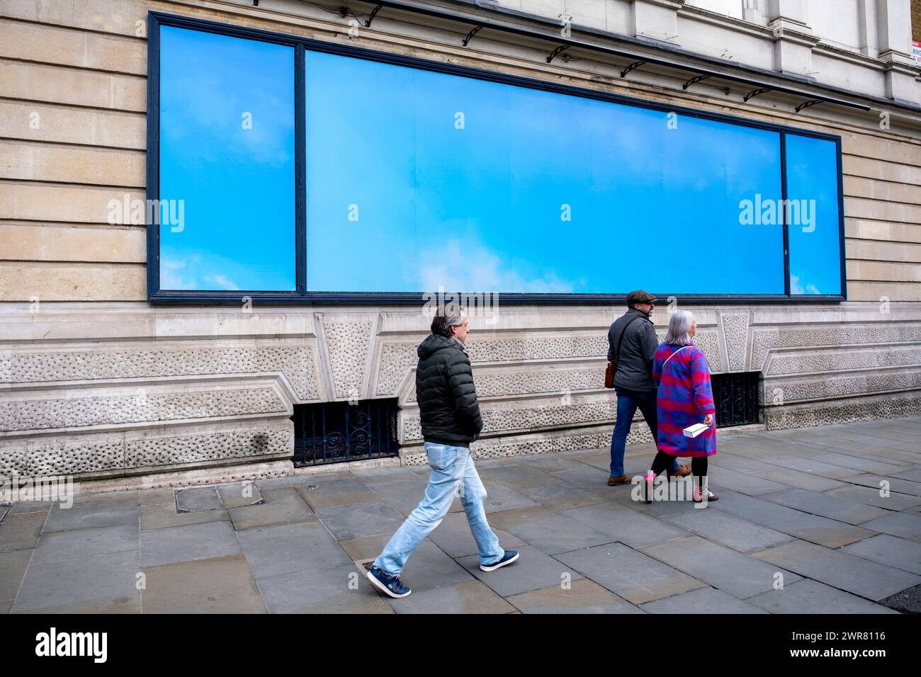 People interacting with a minimal blue billboard sized advertising poster featuring a simple image of a blue sky outside the Garrick Theatre for the play For Black Boys Who Have Considered Suicide When the Hue Gets Too Heavy by Ryan Calais Cameron on 6th March 2024 in London, United Kingdom. Stock Photo