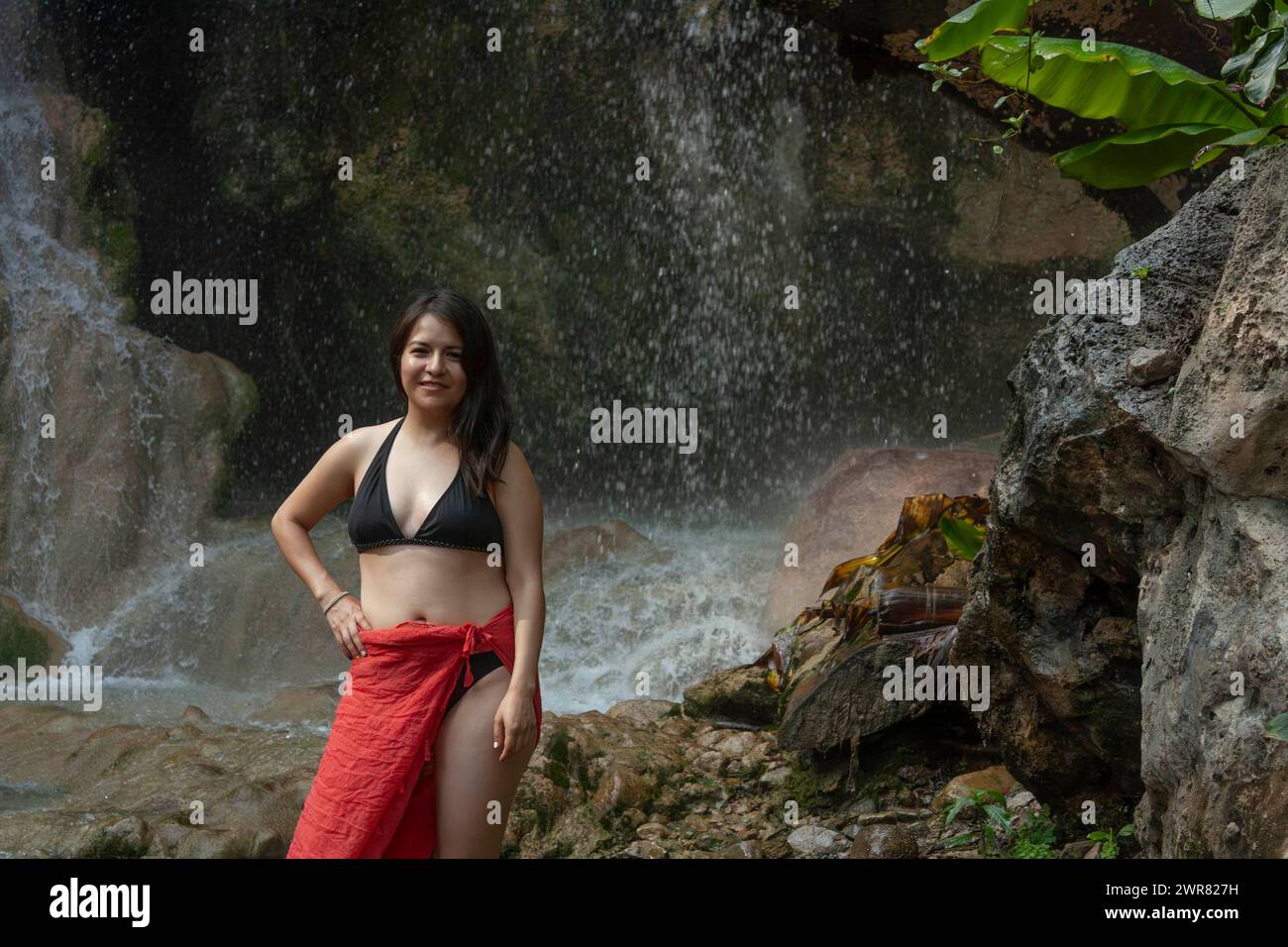 Woman enjoying the cool breeze next to the fresh water waterfall natural environment moss rocks and water in Hidalgo, State of Mexico. Stock Photo
