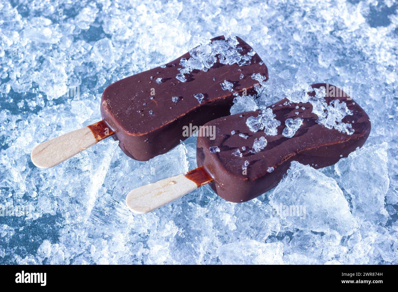 The Chocolate Coated Ice Cream Bars On Wooden Stick On The Chopped Ice Crystals. Stock Photo