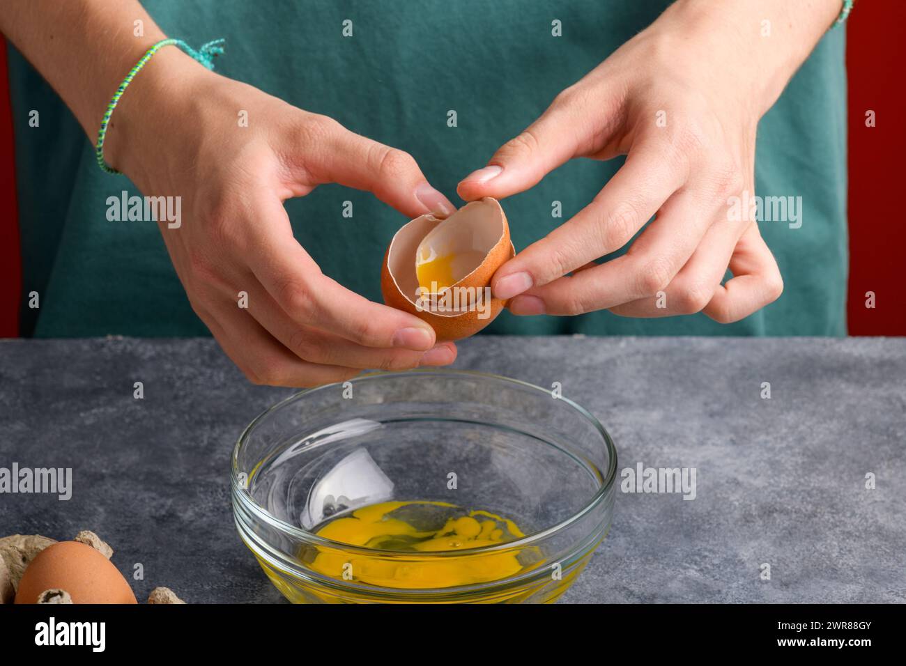 A woman's hand holding the eggshells of breked egg into a clear glass ...