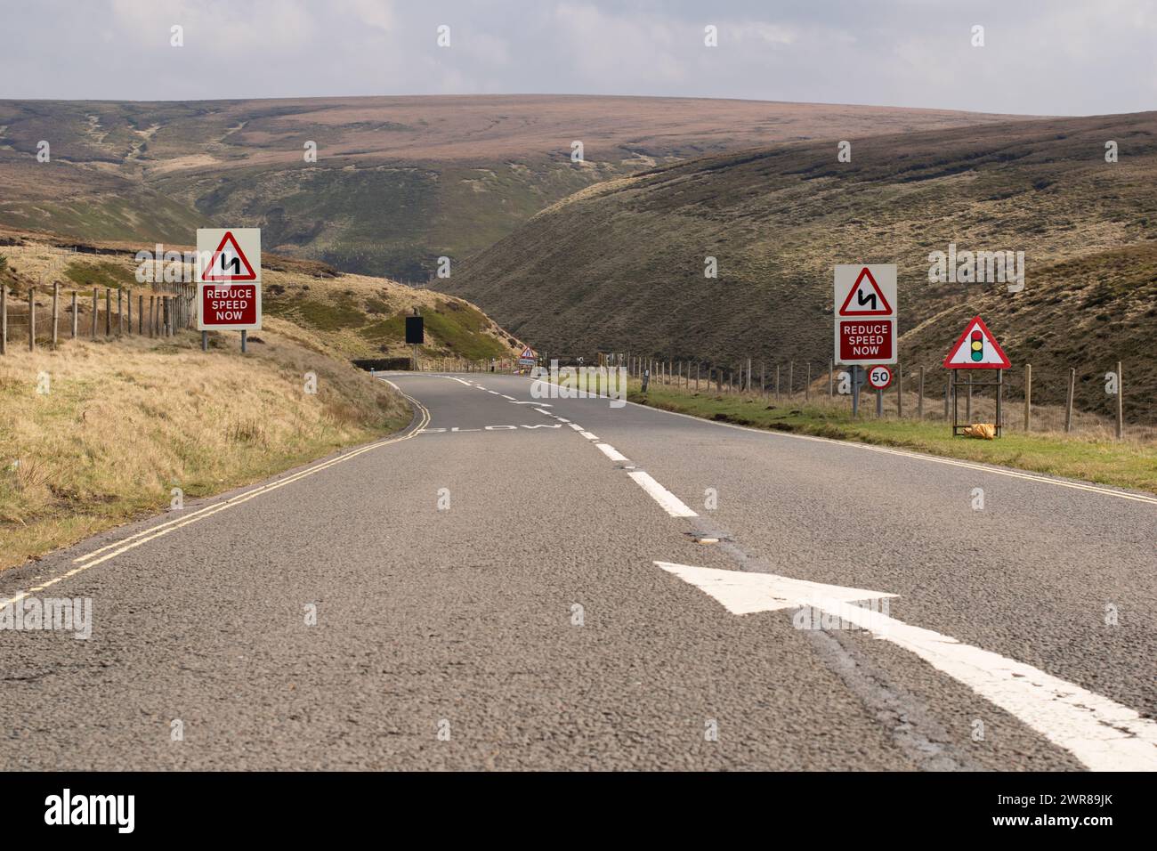 Snake Pass road Derbyshire. Entrance to road descent through the Pennine Hills, Peak District. Reduce Speed sign, keep left and slow sign. Stock Photo