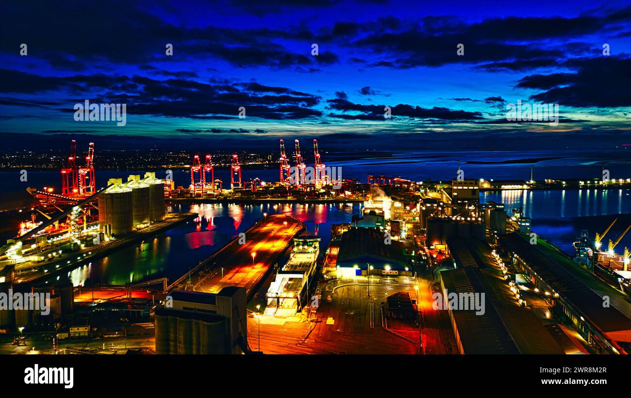 Panoramic night view of a bustling port with illuminated cranes and ...