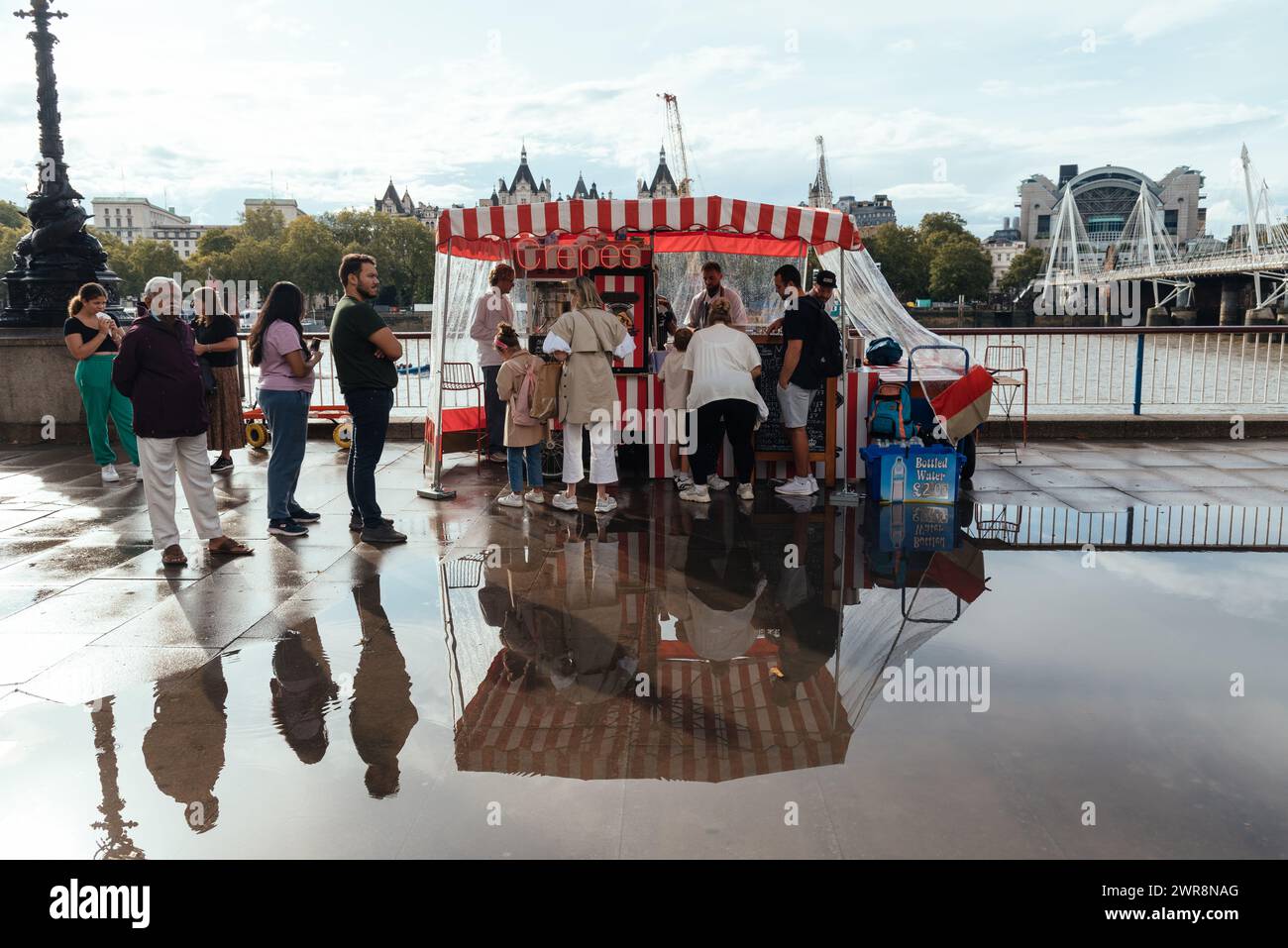 London, UK - August 26, 2023: People enjoying food from crepes food trucks on Thames riverside by London Eye, one of London top tourist attractions. S Stock Photo