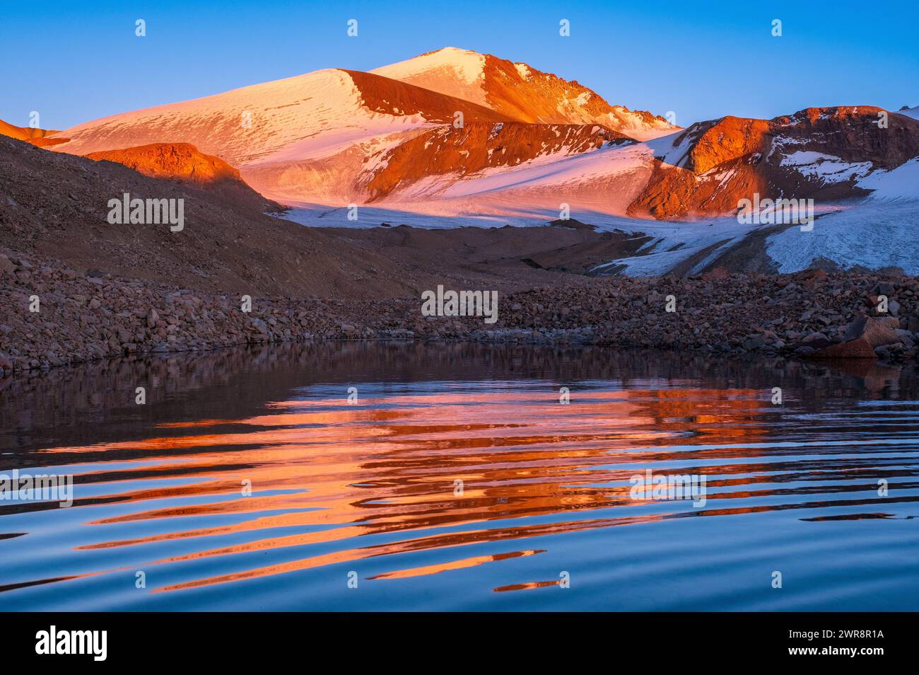 Spectacular reflection of a sunset mountain peak on the water surface ...