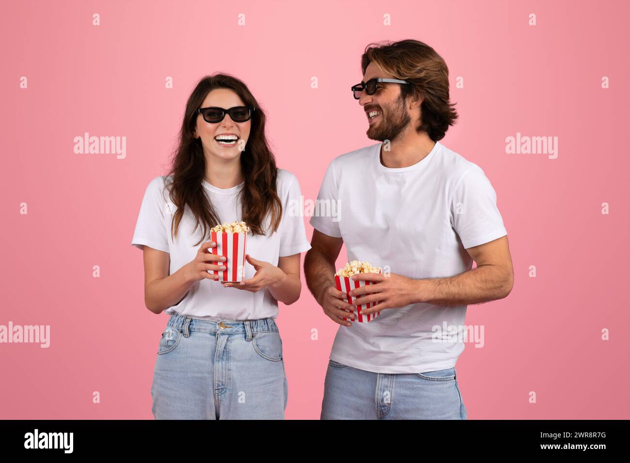 Laughing woman and man wearing 3D glasses and holding red and white striped popcorn boxes Stock Photo
