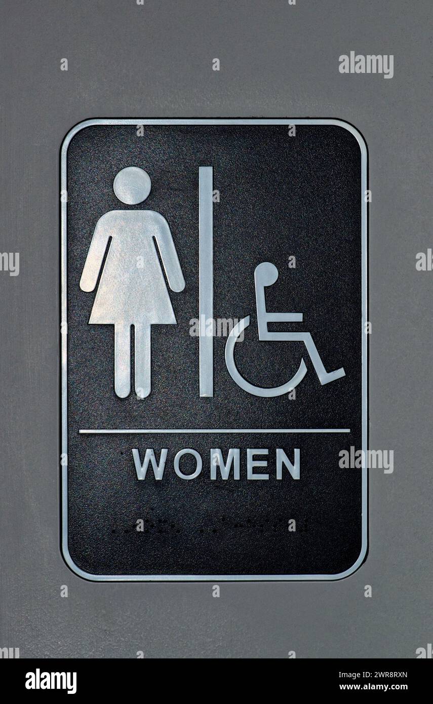 Women's bathroom and handicap sign on a door. Depicts the usage of braille at the bottom of the sign. Stock Photo