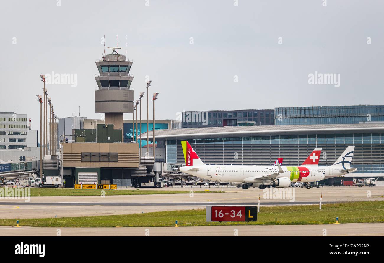 Blick auf den Flughafen Zürich mit dem Terminal A und dem Kontrollturm. Davor bewegt sich ein Airbus A321-251NX von TAP Air Portugal nach der Landung Stock Photo