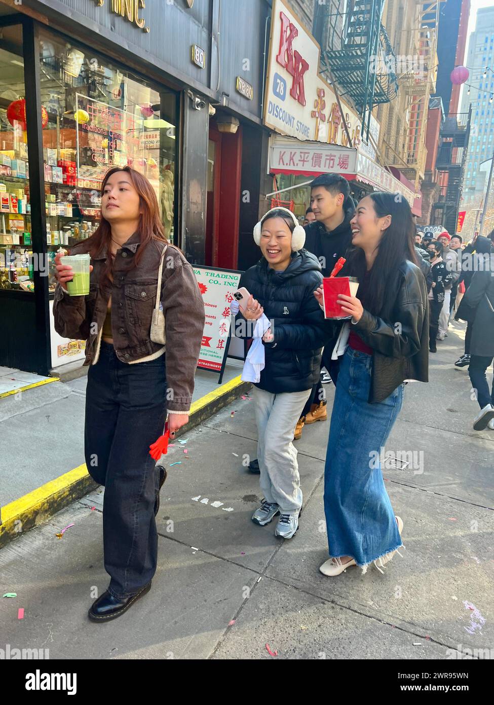 Young Chinese American women walk together in Chinatown on Chinese New Year welcoming in The Year of the Dragon in Chinatown, New York City. Stock Photo