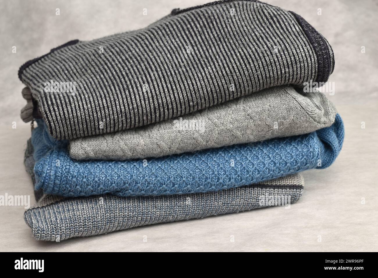 A view of several sweaters folded into a low pile. Stock Photo