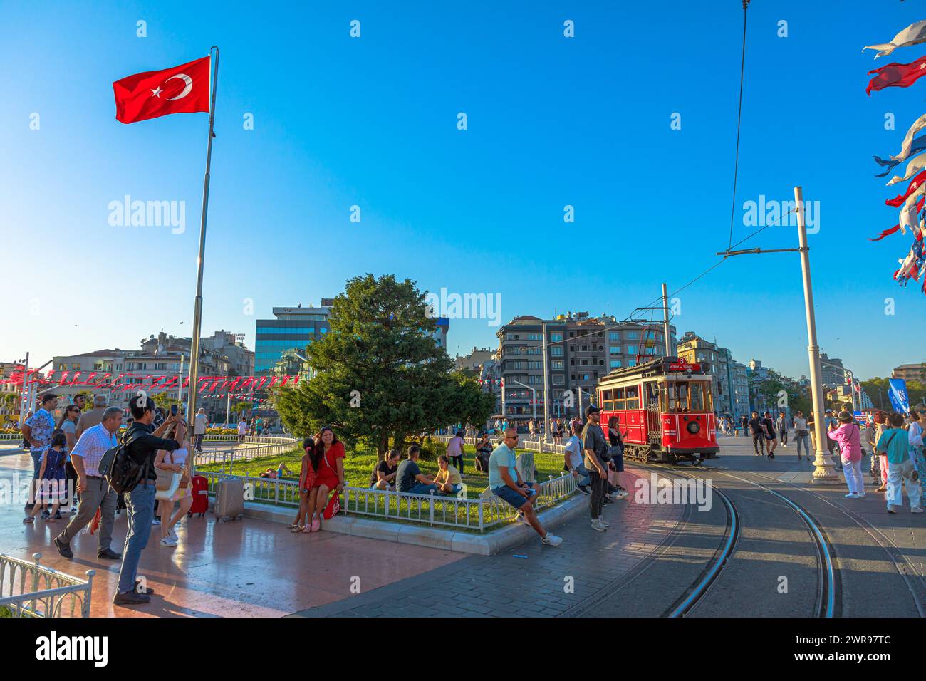 Istanbul, Turkey - Aug 2,2023: Vibrant urban life captures at taksim square with iconic red tram and turkish flag Stock Photo