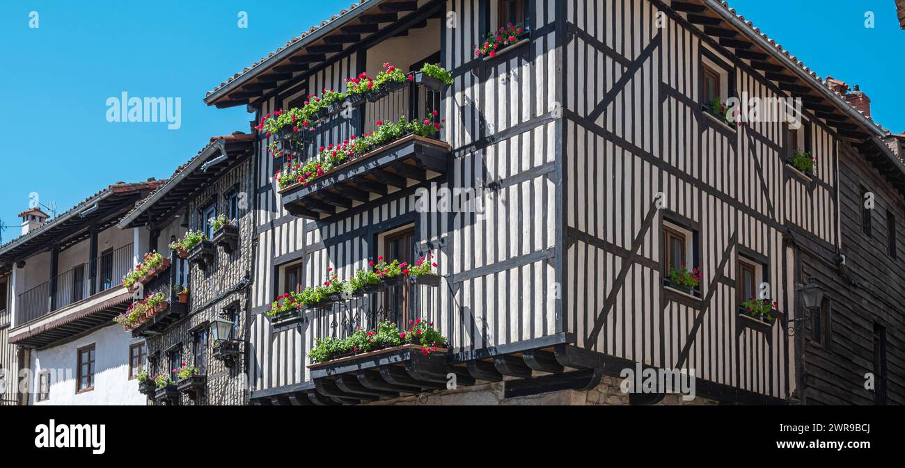 A Traditional architecture houses with wooden beamed facades and balconies adorned with pots and pots in the beautiful villa of La Alberca, Spain Stock Photo