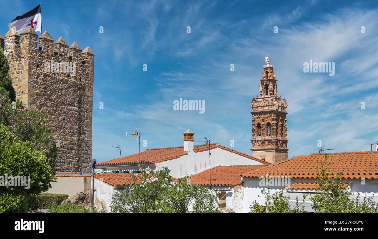 Torreón siglo XIII con bandera de la orden templaria y campanario barroco iglesia de san Miguel Arcángel en la villa de Jerez de los Caballeros, Españ Stock Photo