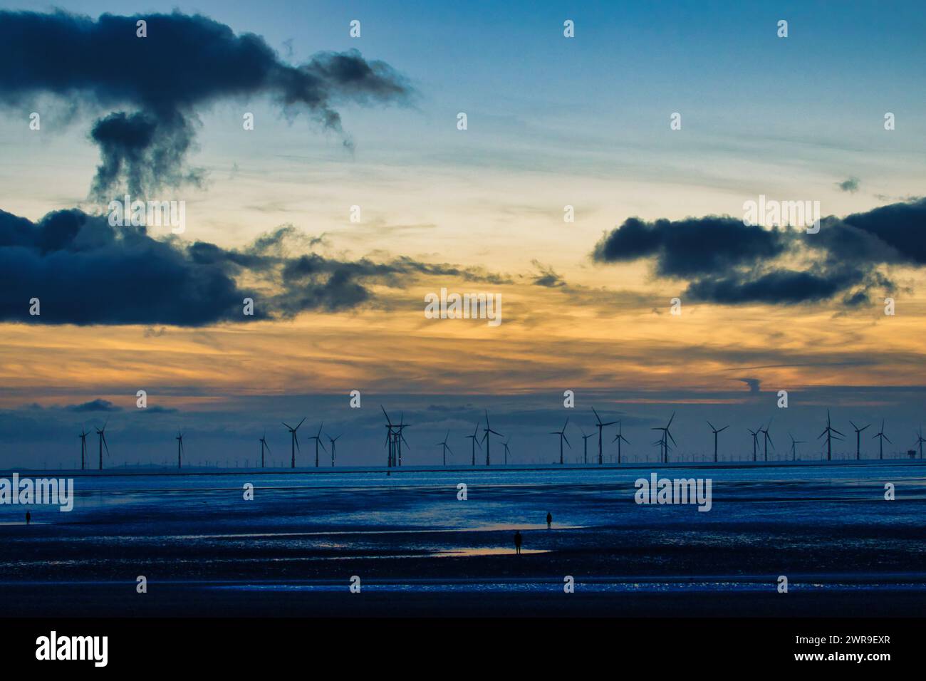 Serene sunset over a wind farm with silhouettes of turbines and ...