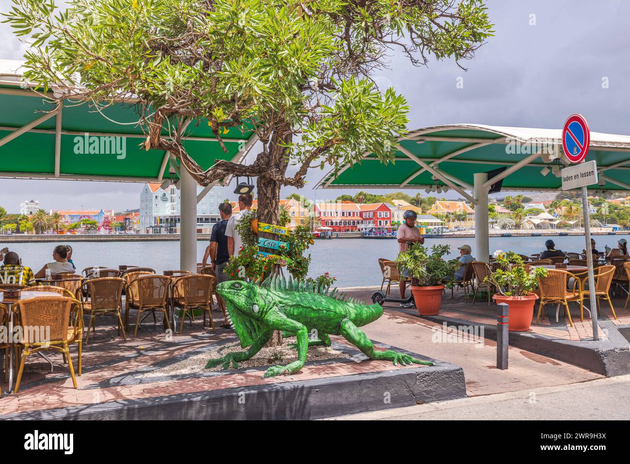 Large green iguana figure at the entrance of a coastal outdoor café on Saint Anna Bay. Curacao. Willemstad. Stock Photo