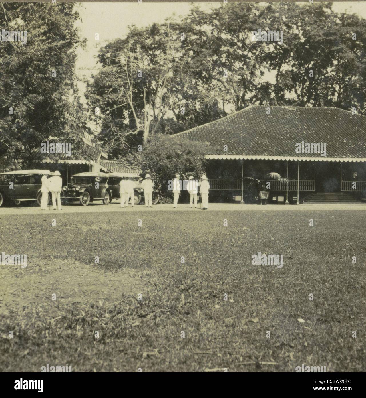 Country house with a few men and cars in front of it, possibly on Borneo, anonymous, Indonesia, 1900 - 1940, cardboard, gelatin silver print, height 90 mm × width 178 mm, stereograph Stock Photo
