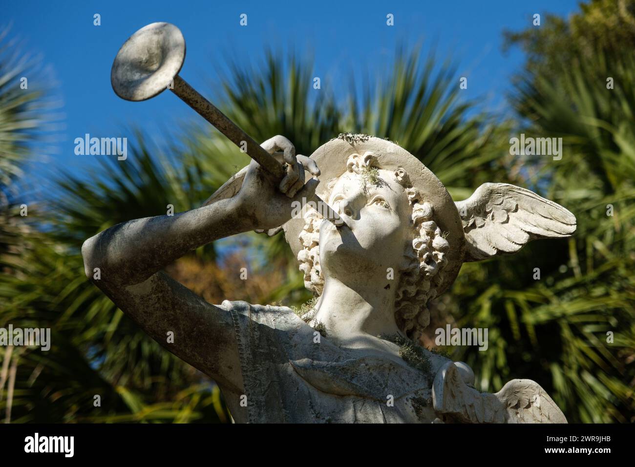 Statue of Mercury (Hermes) blowing a horn surrounded by palm trees. Stock Photo