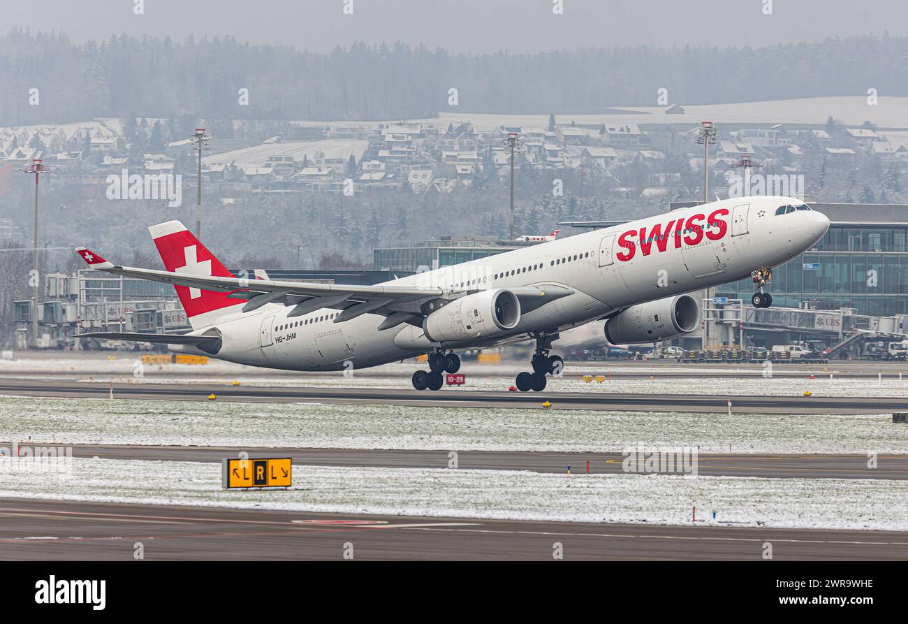 Ein Airbus A340-313X von Swiss International Airlines startet von Startbahn 16 des sich in winterlicher Landschaft befindlichen Flughafen Zürich. Regi Stock Photo