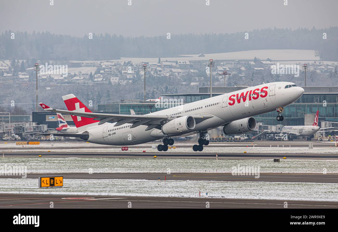 Ein Airbus A340-313X von Swiss International Airlines startet von Startbahn 16 des sich in winterlicher Landschaft befindlichen Flughafen Zürich. Regi Stock Photo