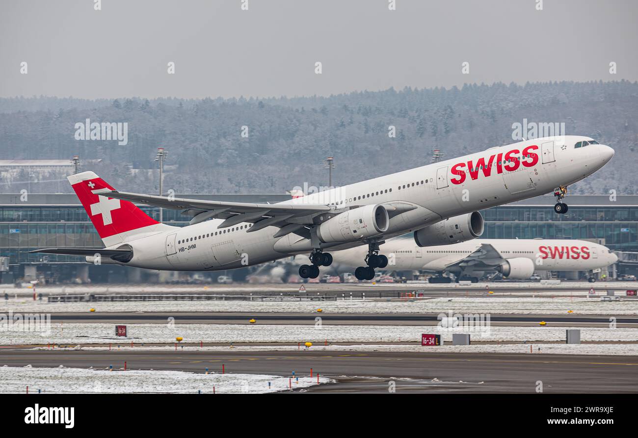 Ein Airbus A340-313X von Swiss International Airlines startet von Startbahn 16 des sich in winterlicher Landschaft befindlichen Flughafen Zürich. Regi Stock Photo