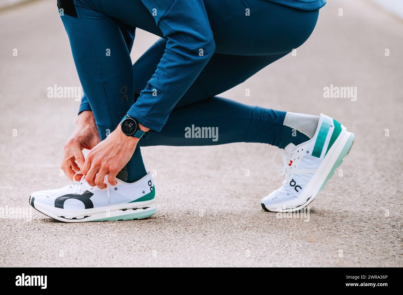 GENEVA, SWITZERLAND, MARCH 10. 2023: On Cloudboom Echo 3, On super shoes, a marathon runner ties his shoes on the road before race. Stock Photo
