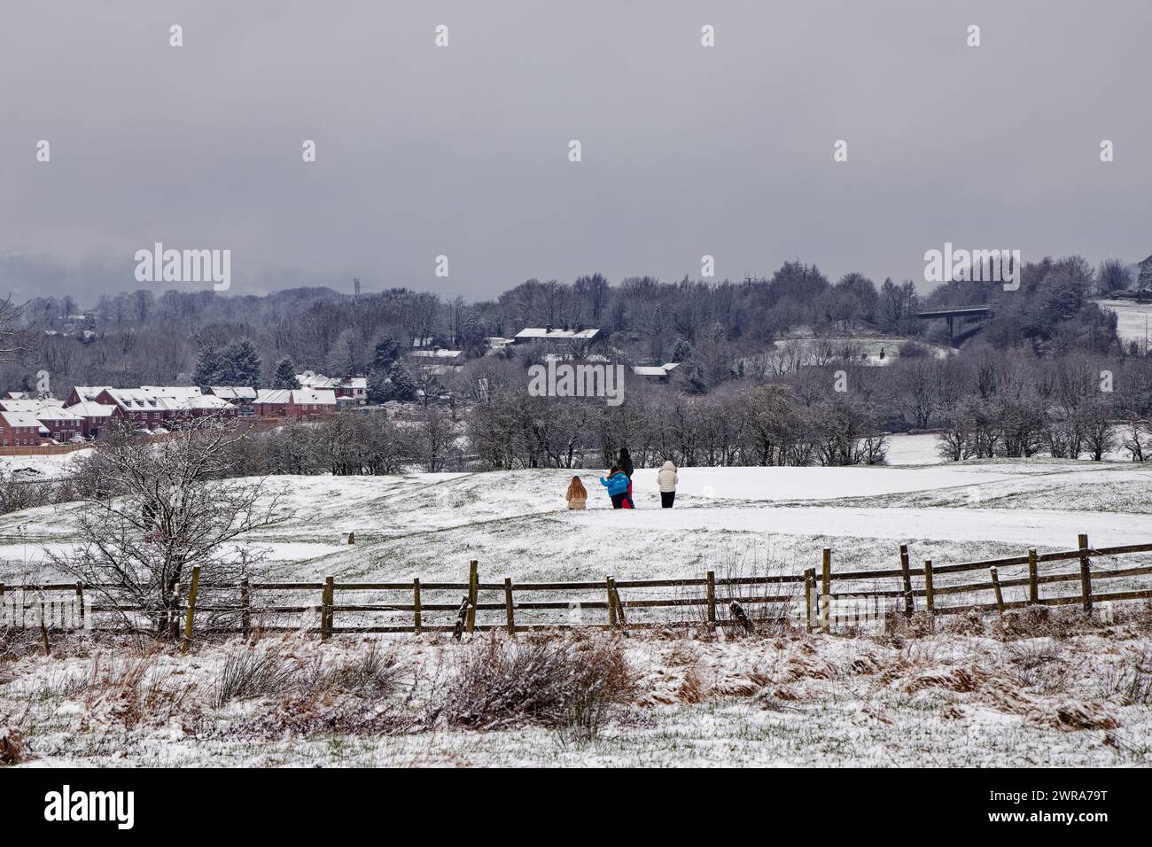 Family walk across a snowy golf course at Walmersley, Bury, Greater Manchester. Stock Photo