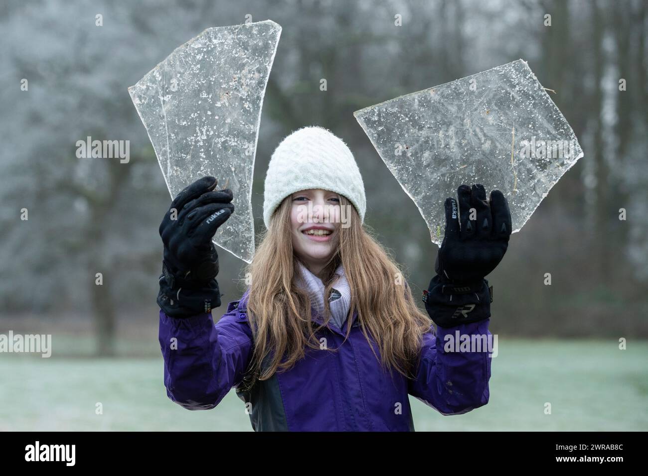 07/01/21   After overnight temperatures plunged well below zero, Freya Kirkpatrick (13), uses her head to smash chunks of ice, collected from frozen p Stock Photo