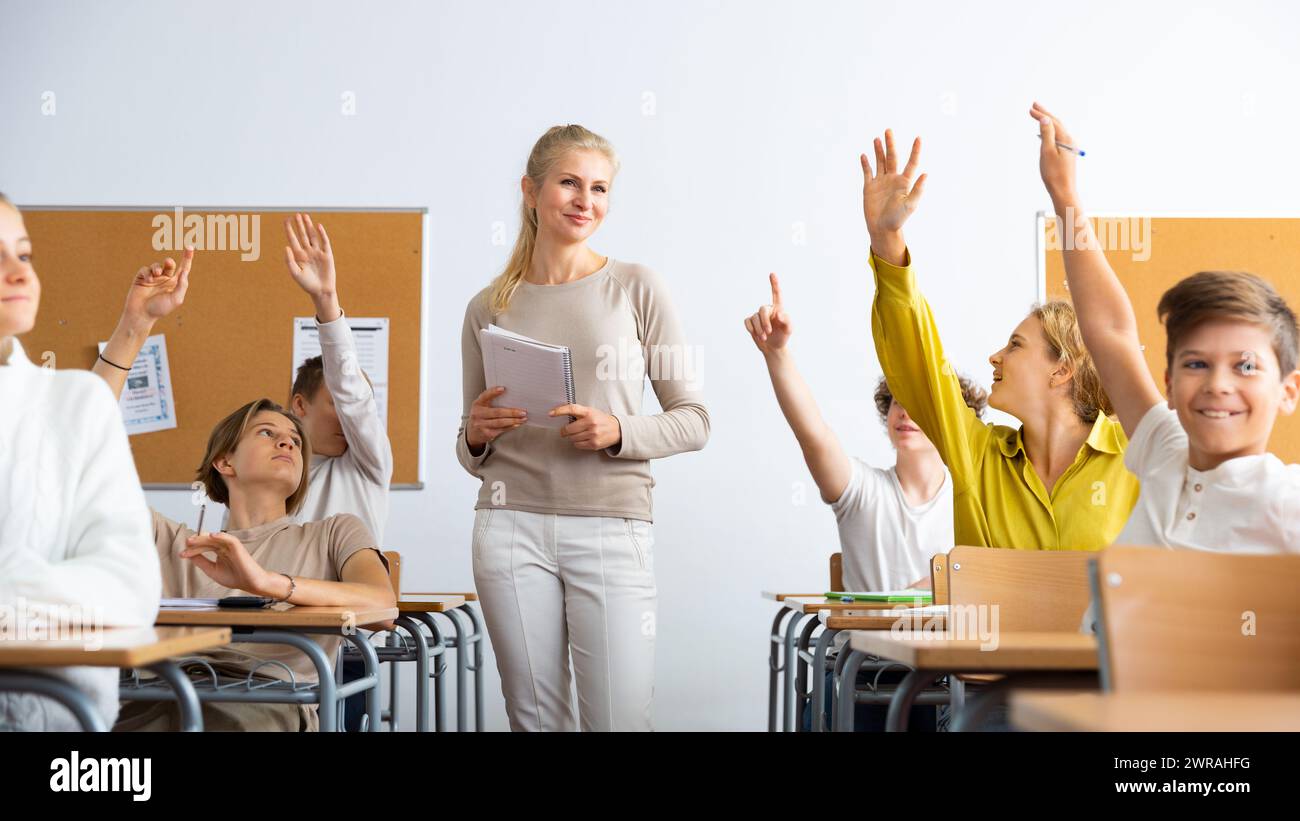School pupils raise their hands up in classroom Stock Photo - Alamy