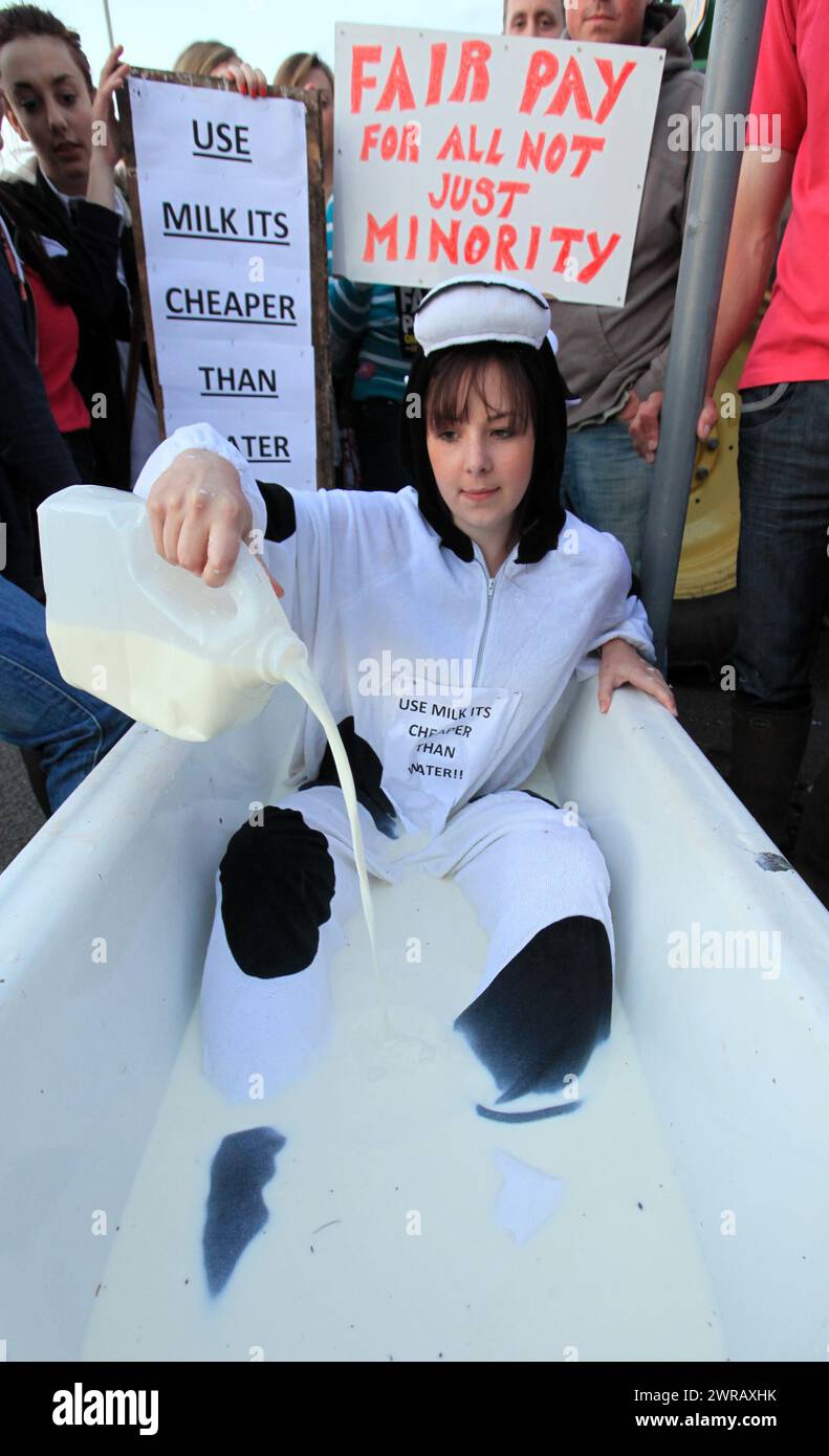 22/07/12..Dressed in a cow suit, and with a sign saying: 'USE MILK ITS CHEAPER THAN WATER', Katie Weaver, 25, from Market Drayton, sits in a bath full Stock Photo