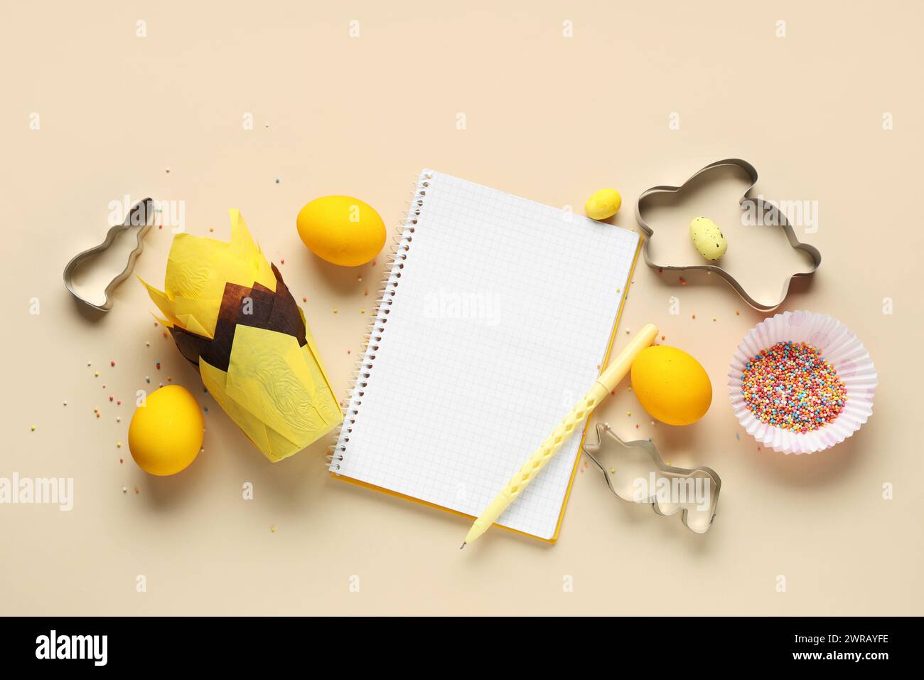 Blank notepad for recipes with pen, Easter eggs and baking tools on beige background Stock Photo