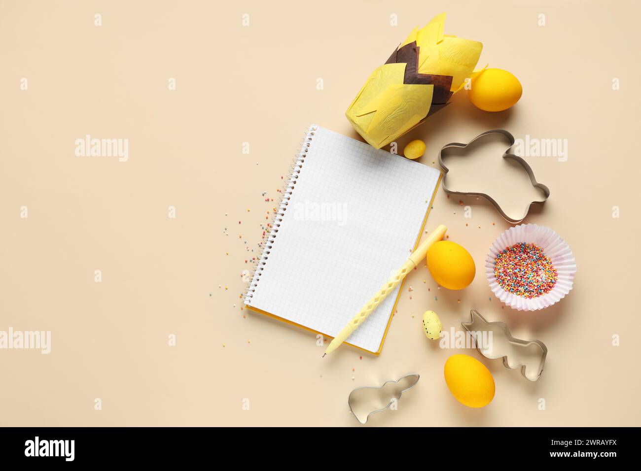 Blank notepad for recipes with pen, Easter eggs and baking tools on beige background Stock Photo