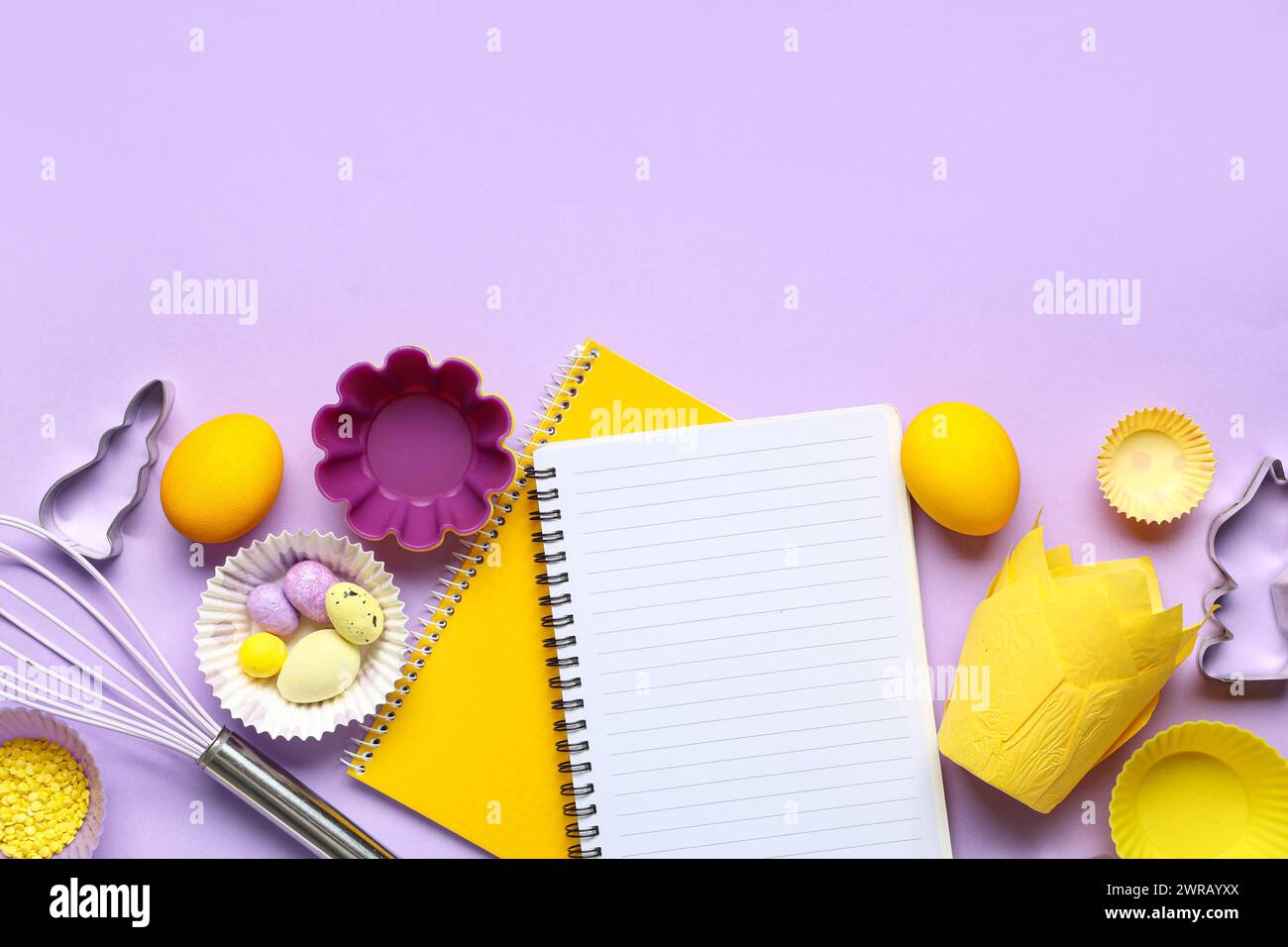 Blank notepads for recipes with Easter eggs and baking tools on lilac background Stock Photo